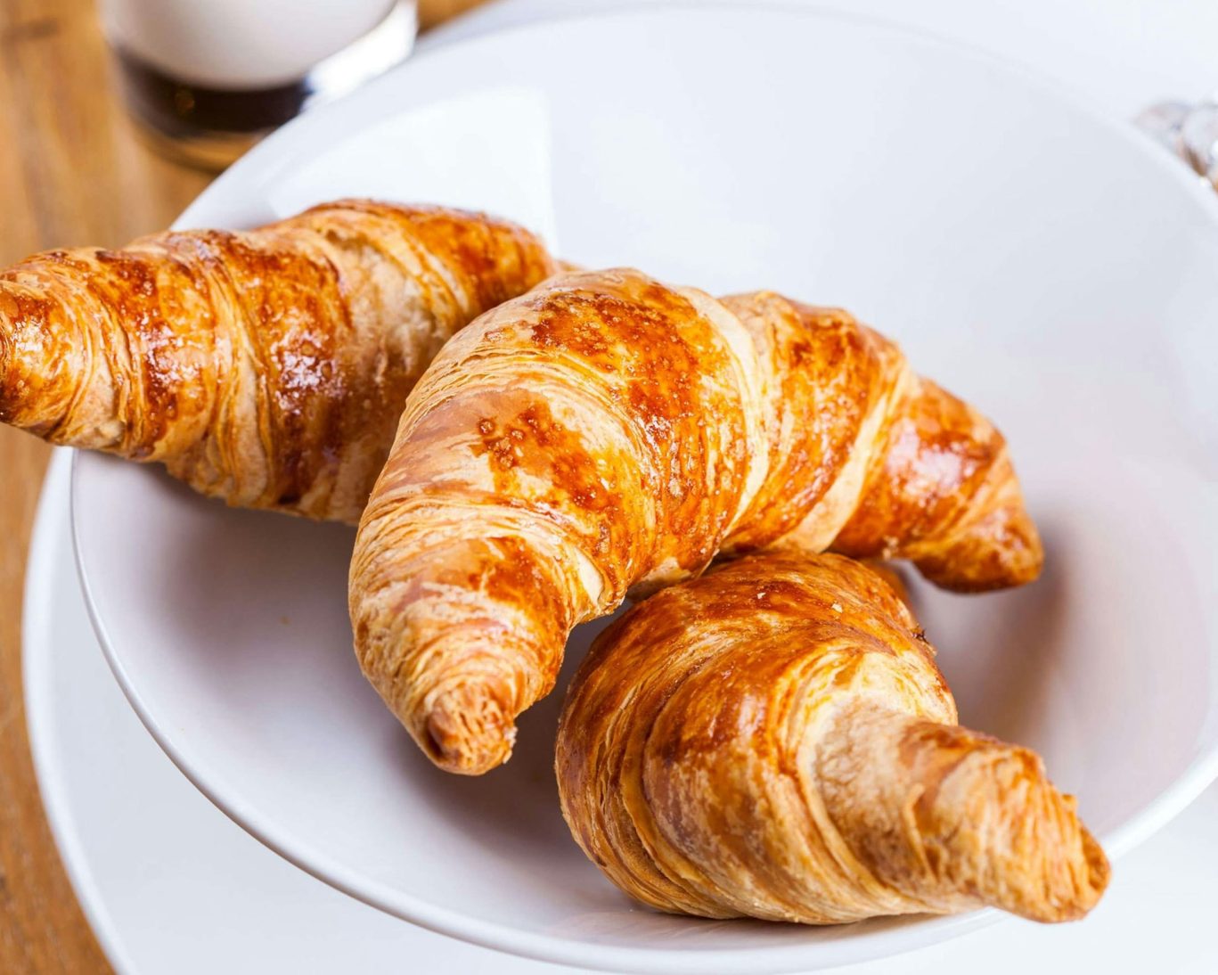 Freshly baked croissants served on a white plate for hotel continental breakfast.
