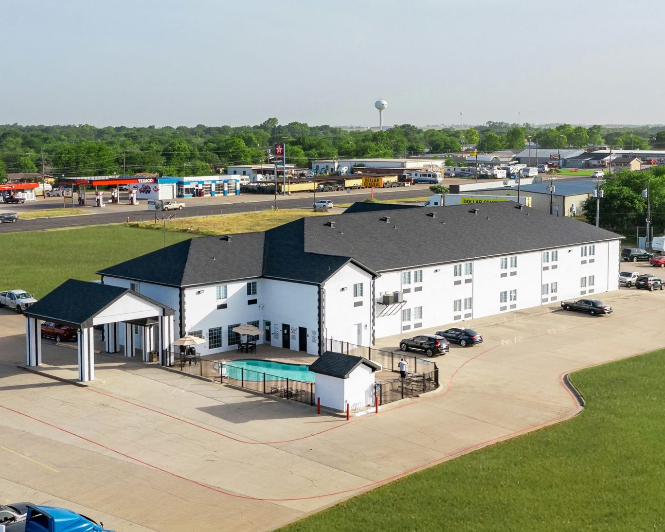 Aerial view of Atria hotel with parking lot and outdoor pool, located near shops and gas stations.