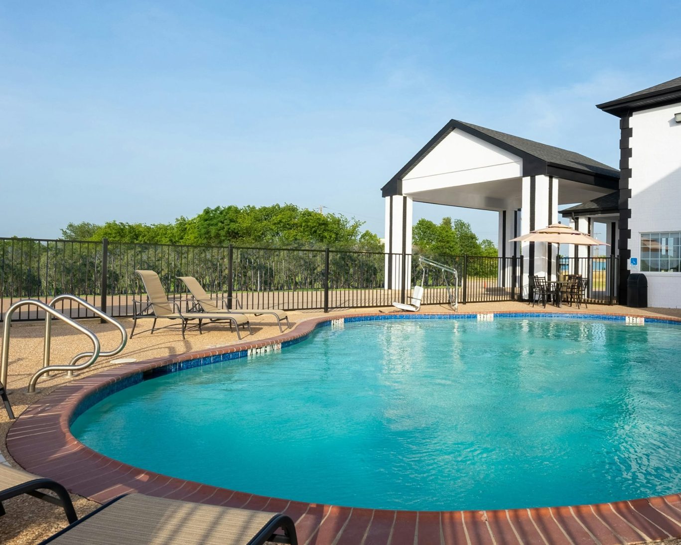 Outdoor swimming pool with lounge chairs and umbrellas at Atria hotel.