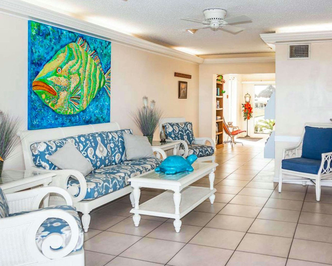 Coastal-themed hotel lobby with white furniture and vibrant fish artwork at Belleair Beach hotel.