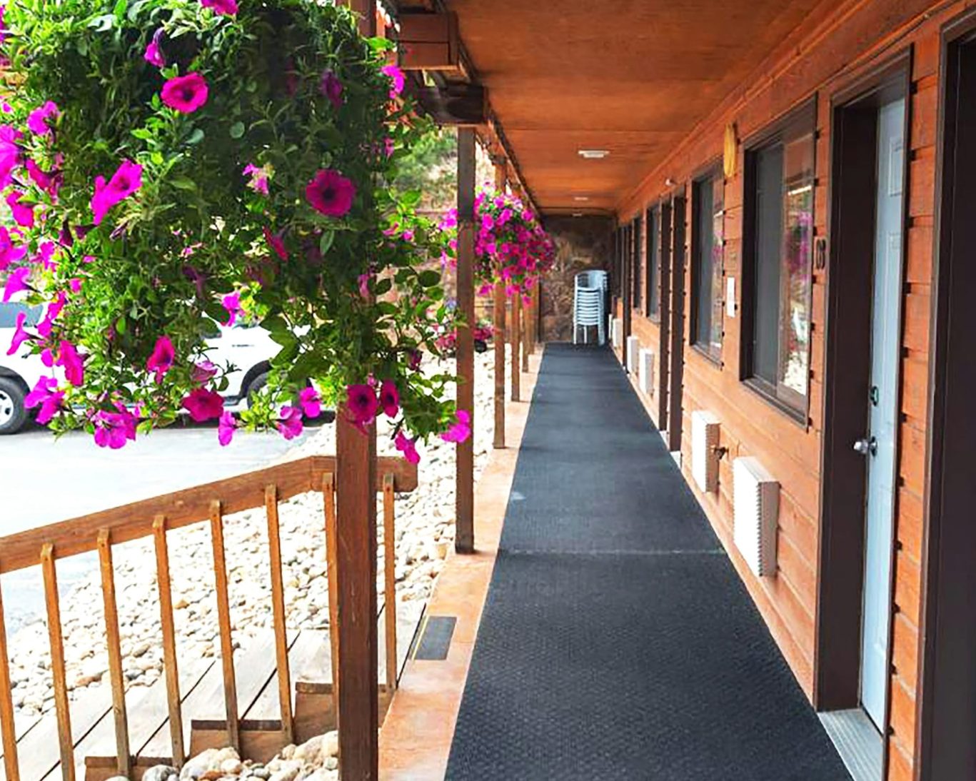 Covered walkway with vibrant pink hanging flowers outside Bighorn Lodge guest rooms.