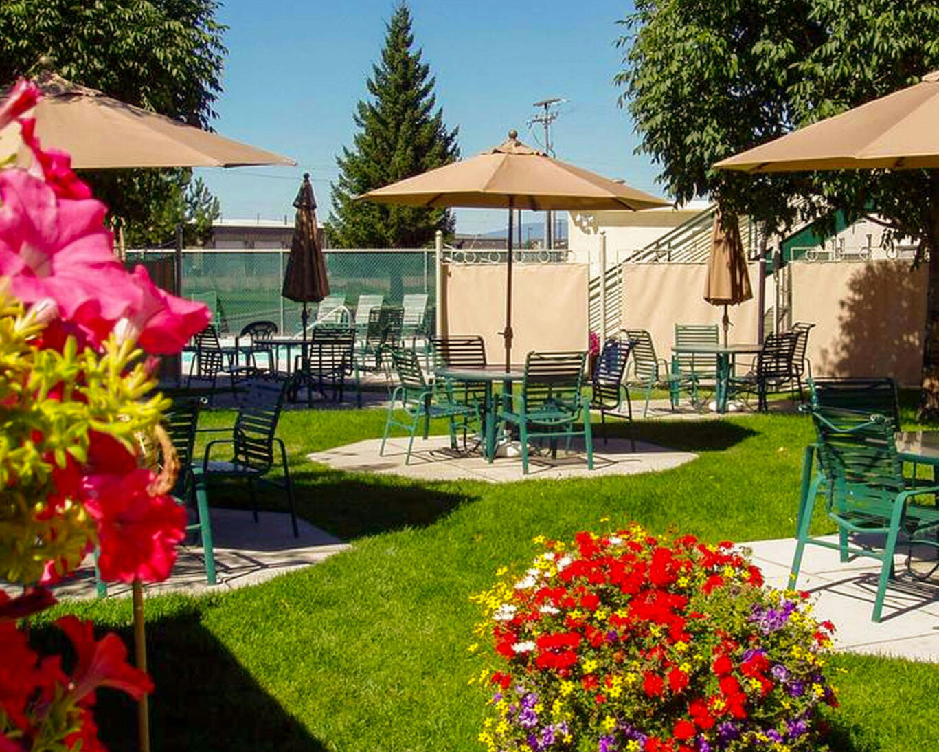 Outdoor patio seating with umbrellas and vibrant flowers at Broadway Inn