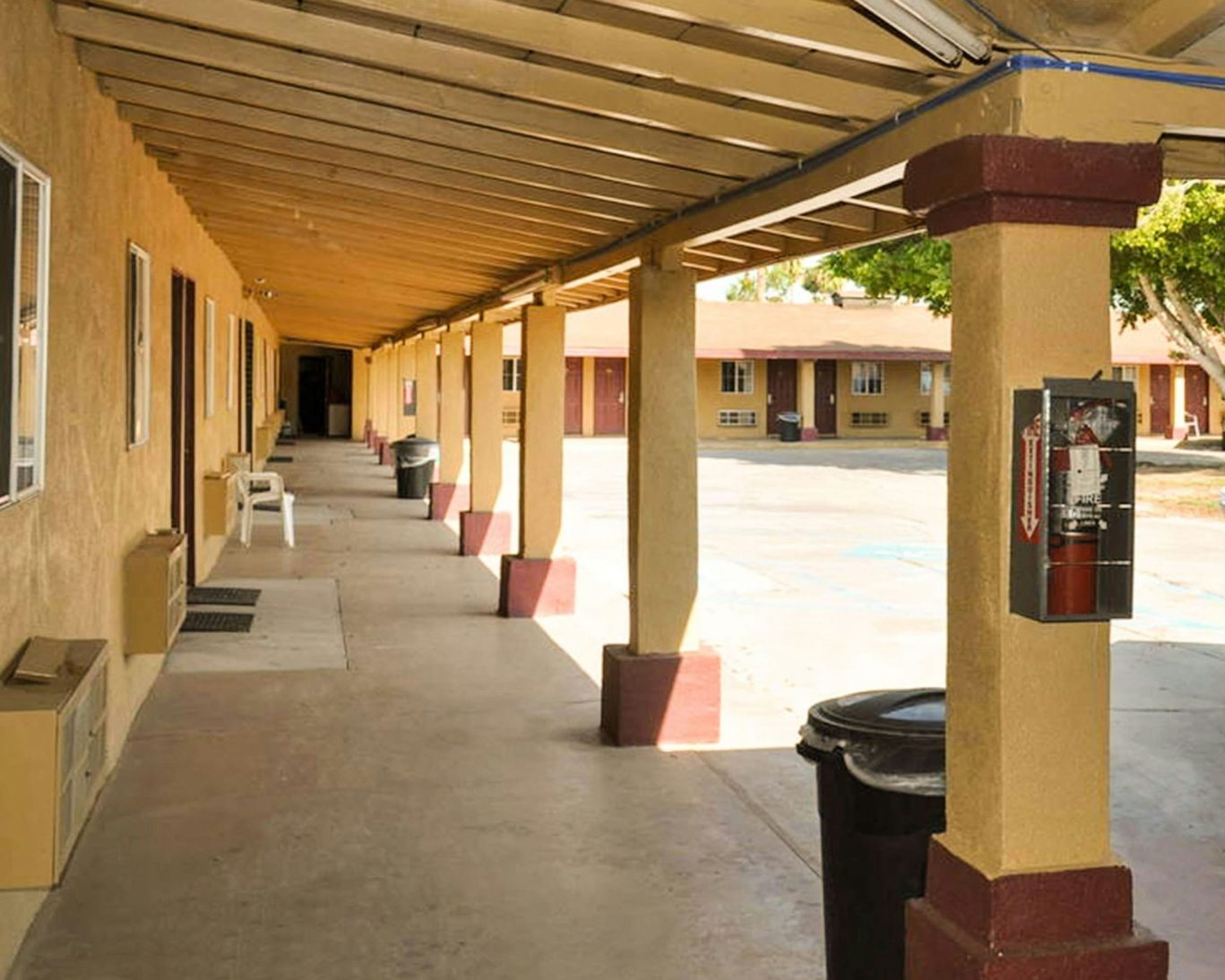 Covered walkway outside California Suites Motel rooms with visible entry doors and fire extinguisher.