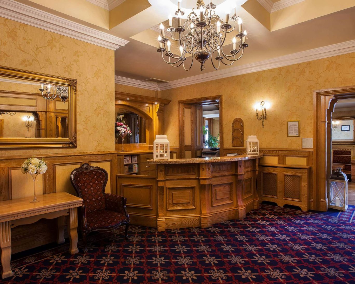 Traditional reception area at The Castle Arch Hotel featuring wood finishes and elegant chandelier.