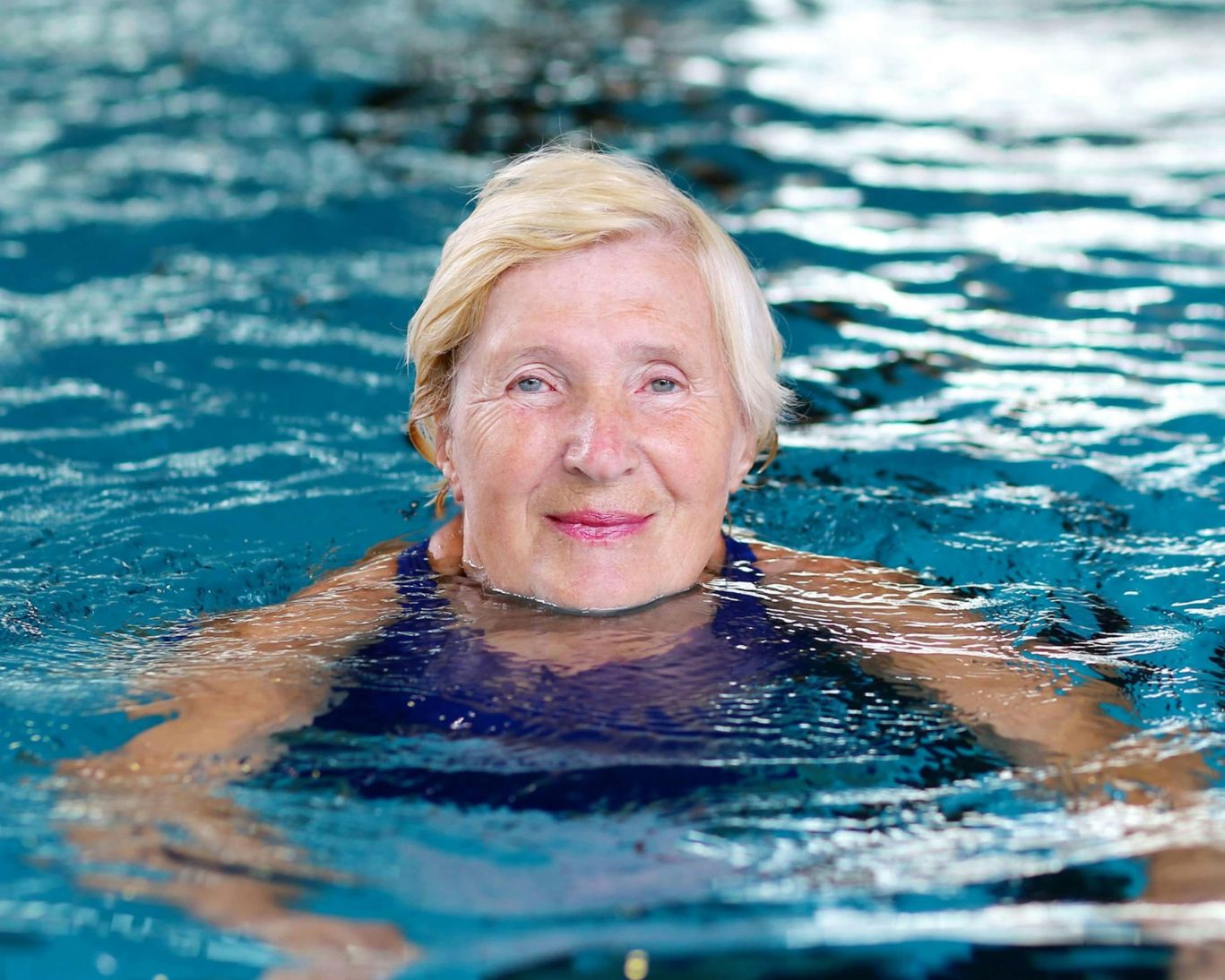 Senior woman enjoying a swim in the heated indoor pool at Colonial Motel.