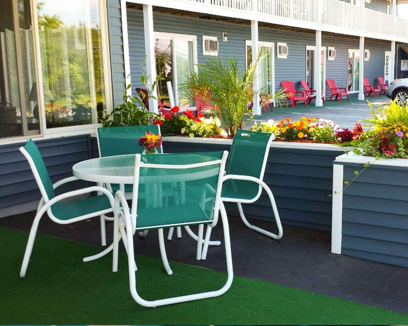 Outdoor seating area with green chairs and vibrant flowers at Colonial Motel.