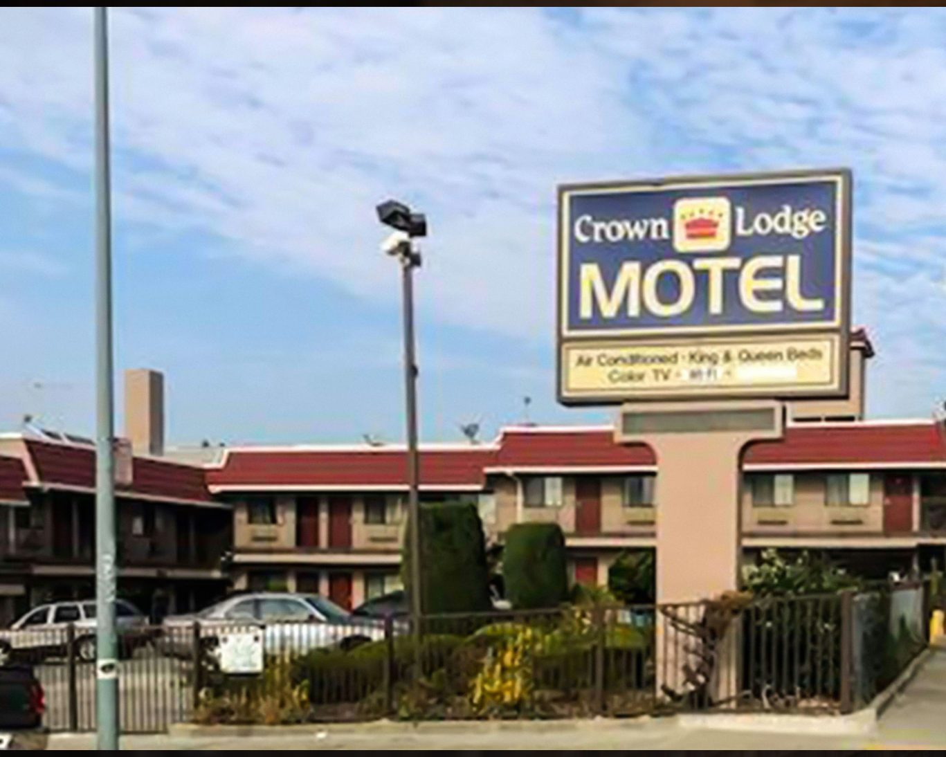 Exterior of Crown Lodge Motel with large roadside sign and two-story guest rooms.