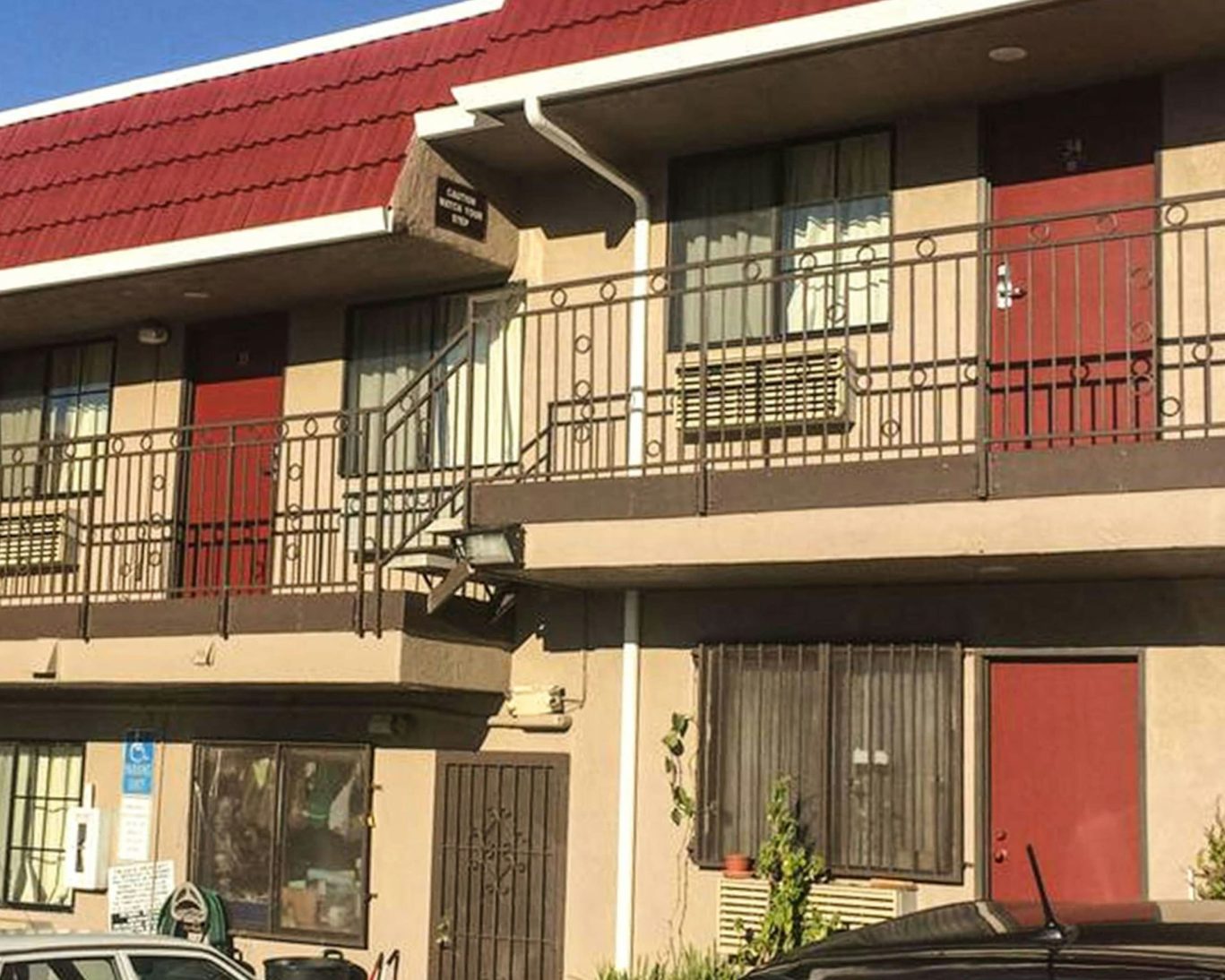 Balcony and guest room entrances at Crown Lodge Motel with red doors and railings.