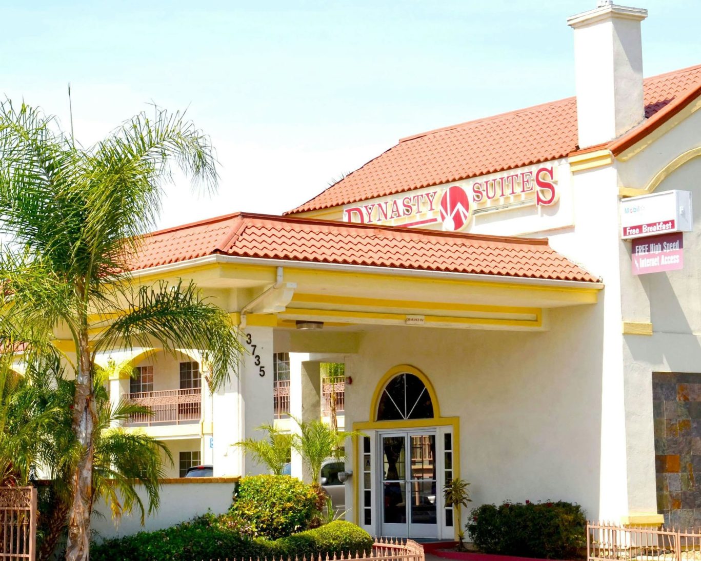 Exterior of Dynasty Suites with red tile roof, tropical landscaping, and welcoming front entrance.