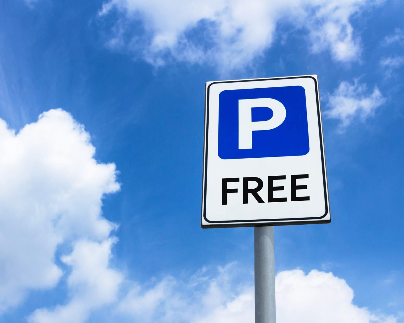 Free parking sign at Dynasty Suites with bright blue sky background.