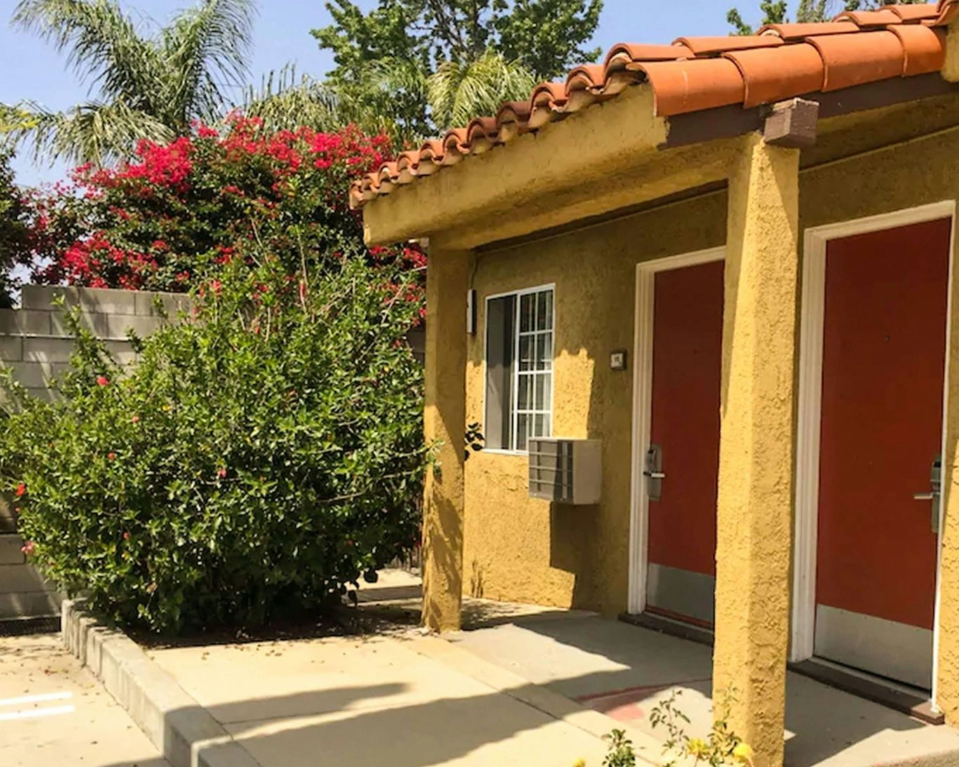 Economy Inn Sylmar guestroom entrances with red doors and tropical landscaping.