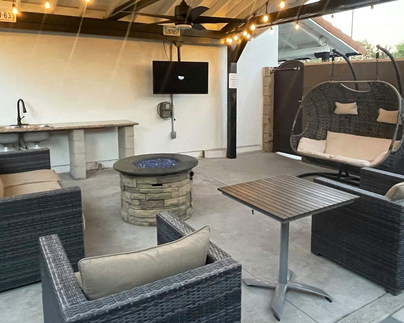 Outdoor seating area at Escondida Motel featuring fire pit, TV, and cozy furniture under string lights.