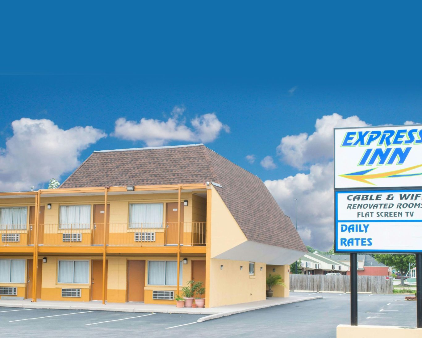 Express Inn Newport exterior with vibrant yellow facade, clear signage, and on-site parking under a blue sky.