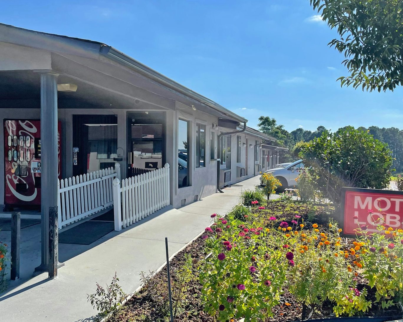 Exterior of Express Inn Thomson with flower beds, vending machine, and motel lobby entrance.