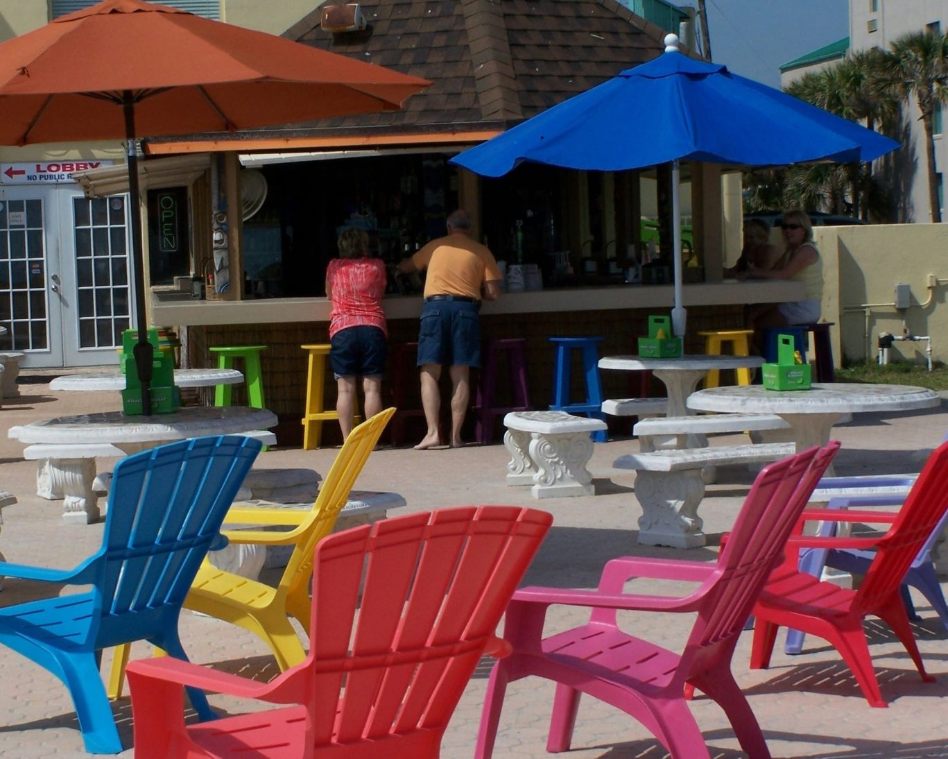 Vibrant outdoor patio at Oasis Tiki Bar featuring colorful Adirondack chairs and shaded seating at Fountain Beach Resort.