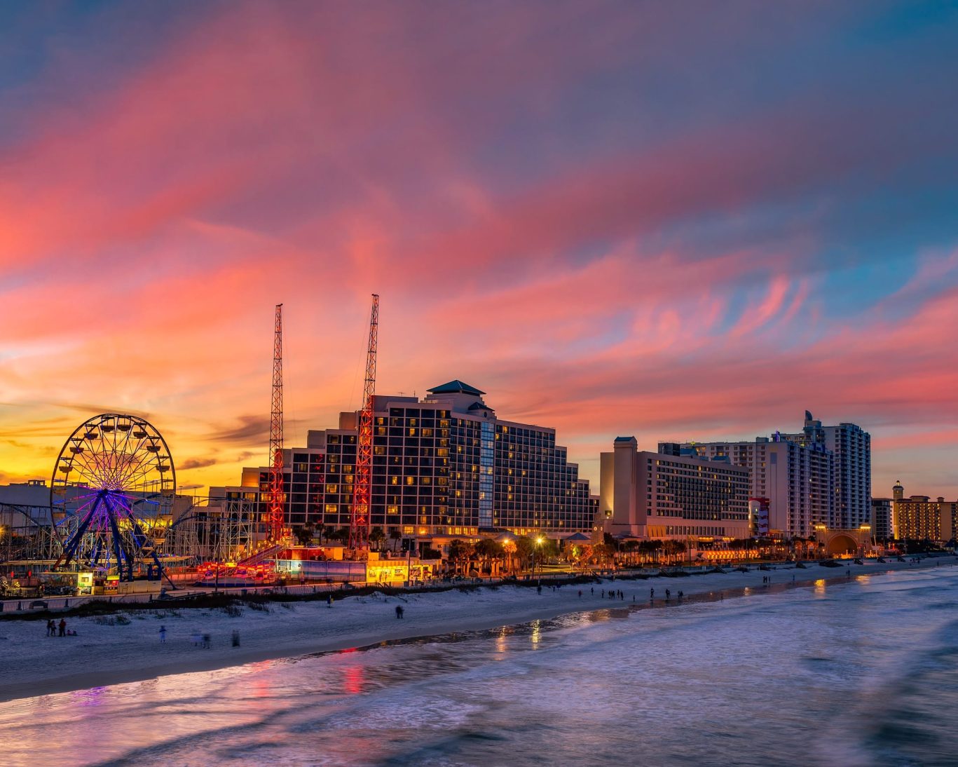 Daytona Beach oceanfront skyline at sunset with Ferris wheel and boardwalk attractions near Fountain Beach Resort.