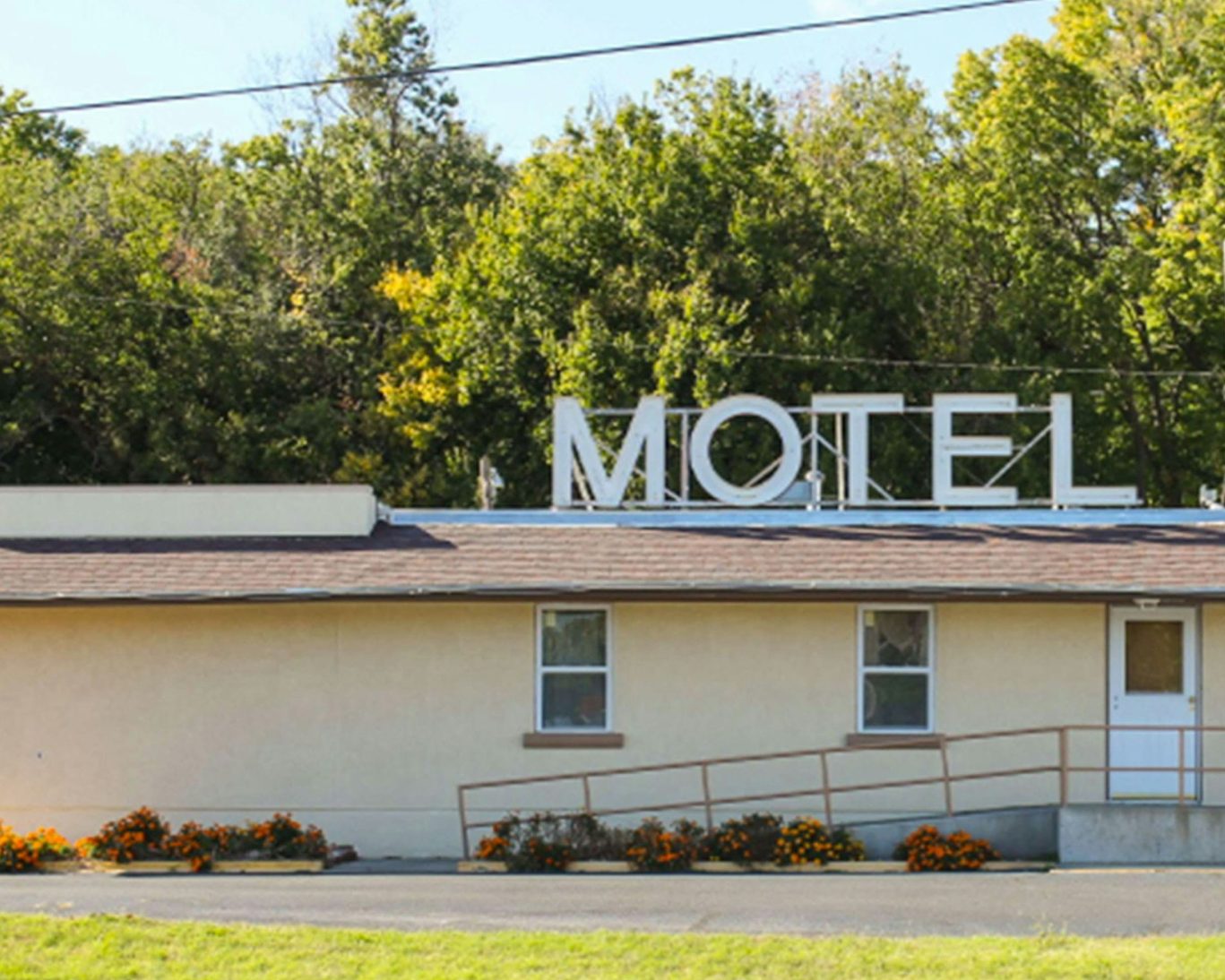 Golden Wheat Motel exterior with large MOTEL sign and flower-lined entrance.