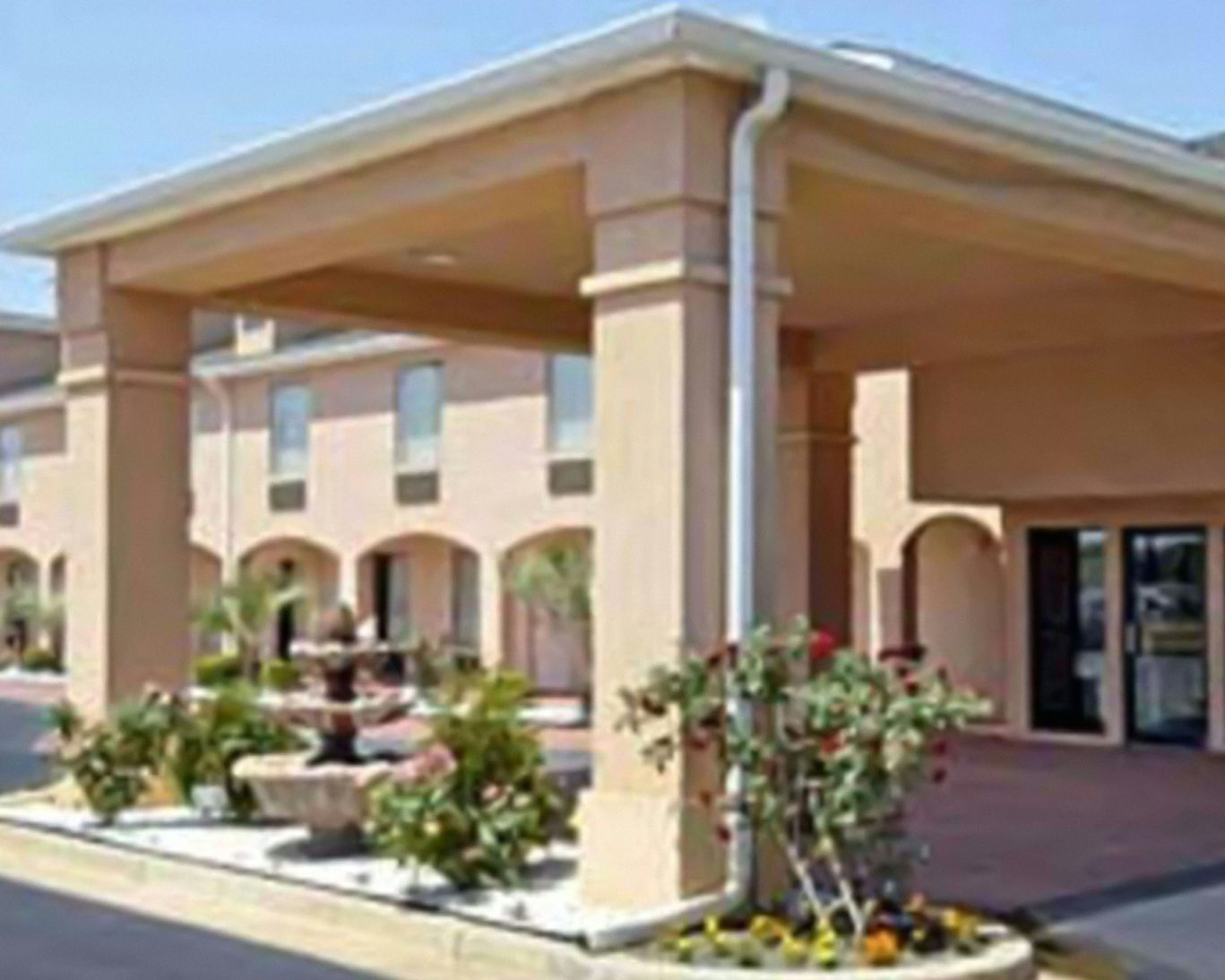 Exterior view of Gray Inn hotel with covered entrance and landscaped fountain area.