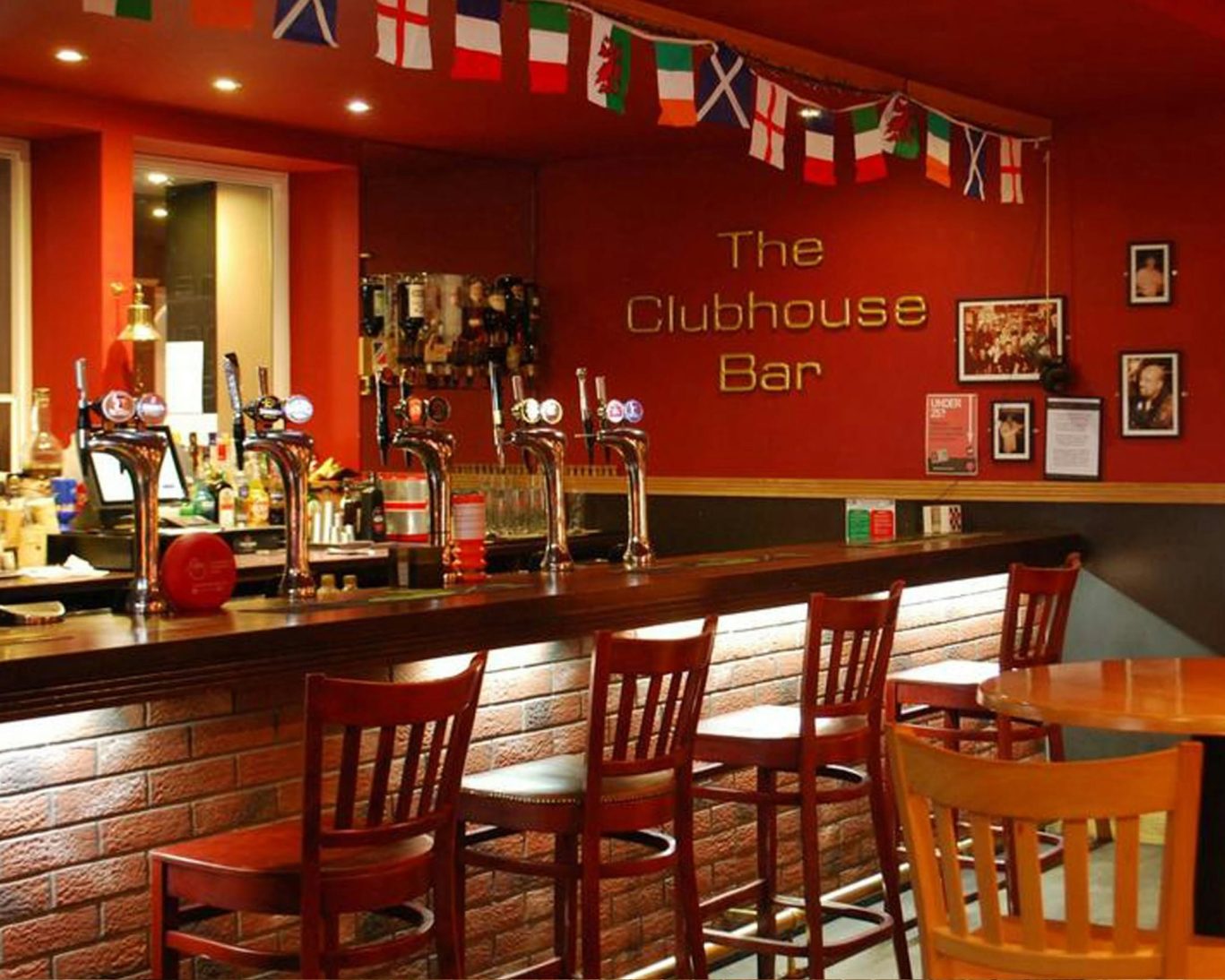The Clubhouse Bar at Great Western Hotel featuring beer taps and international flags.