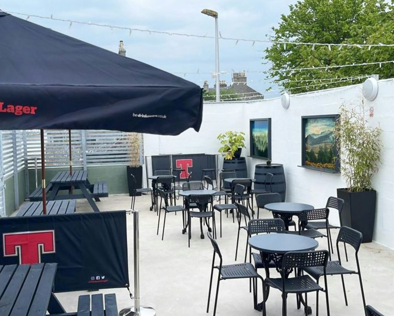 Outdoor beer garden with modern patio seating and branded umbrellas at Great Western Hotel.