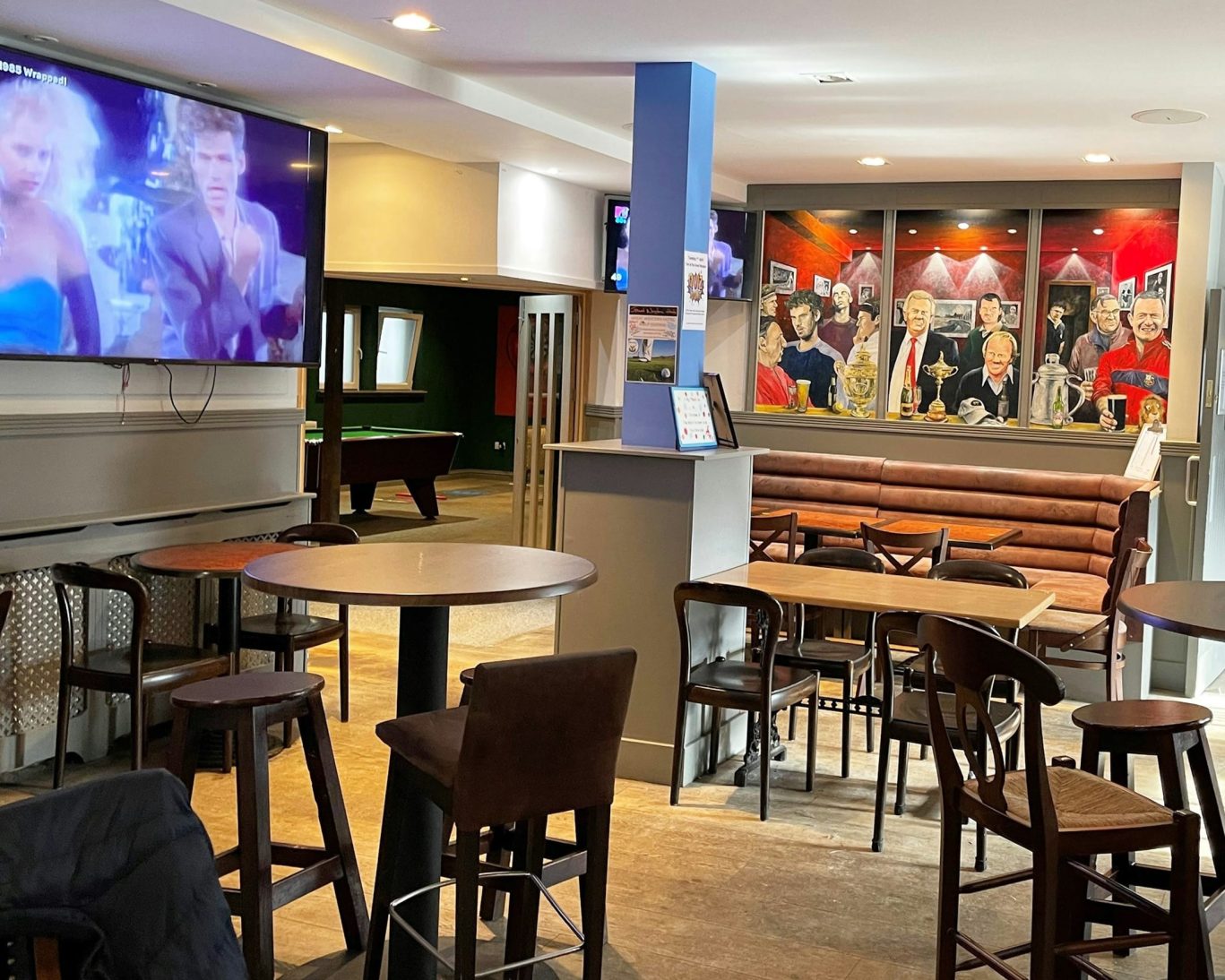 Modern lounge bar at Great Western Hotel with TVs, pool table, and sports-themed mural