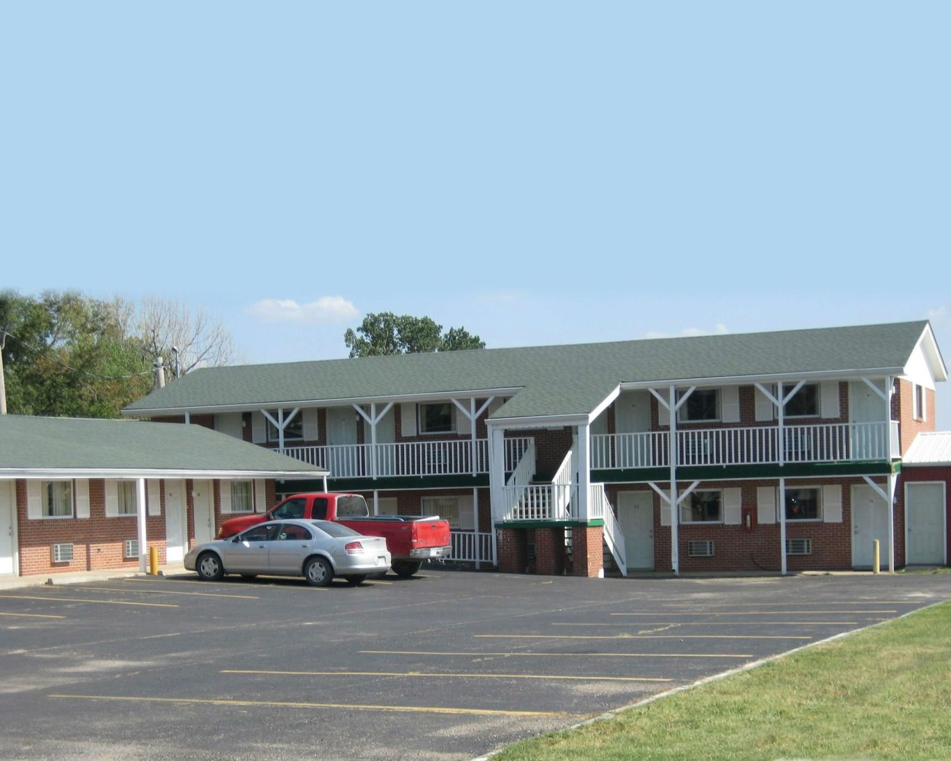 Spacious guest parking area with two-story brick building at Guest House Motel Chanute.
