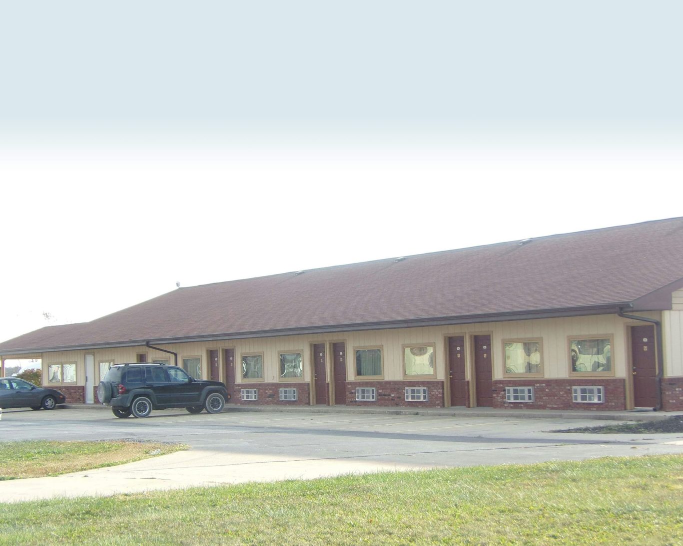 Exterior view of Huggy Bear Motel with guest parking and single-story room entrances.