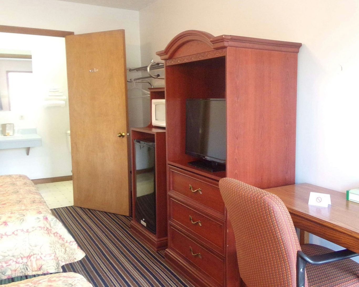 Cozy guest room at Huggy Bear Motel featuring flat-screen TV, microwave, mini-fridge, and workspace.