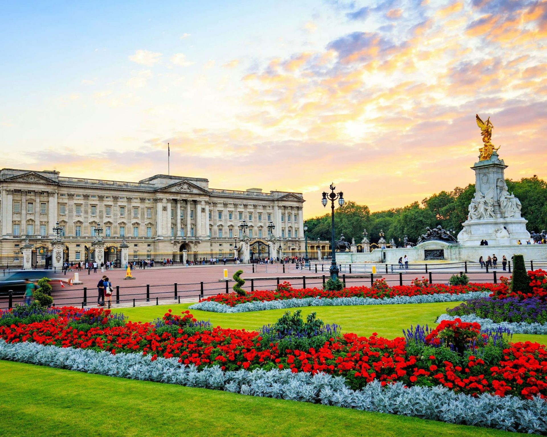 Scenic view of Buckingham Palace with vibrant gardens and sunset sky in London.