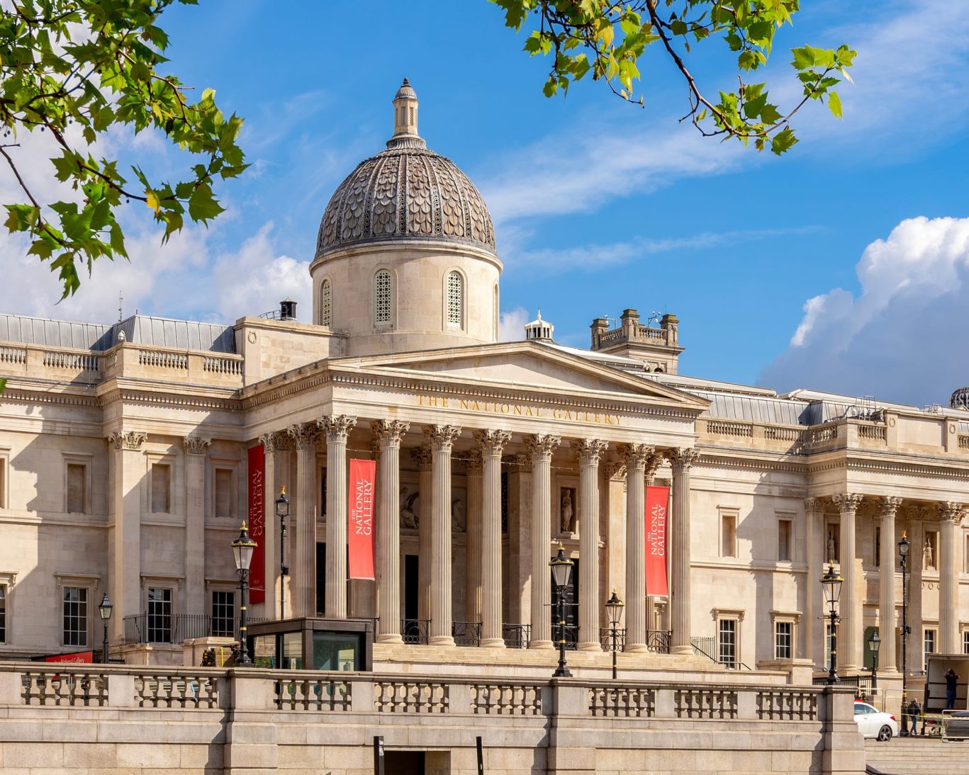 Exterior of The National Gallery in London with classical columns and dome under a clear blue sky.