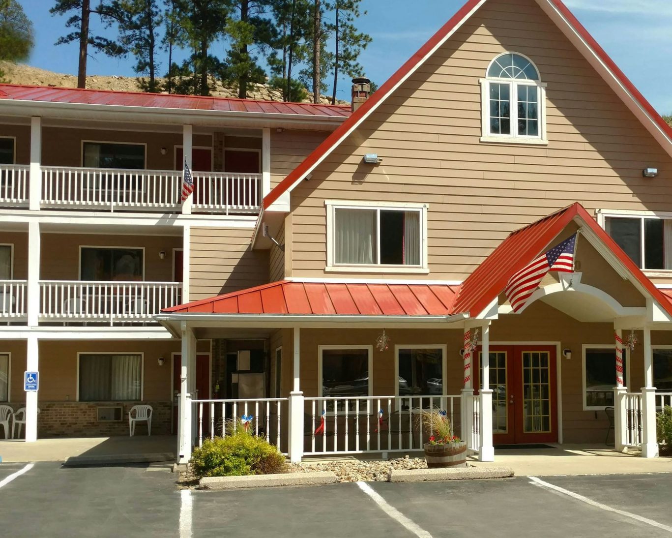 Front exterior of Keystone lodge with red roof, American flags, and accessible guest parking in South Dakota.