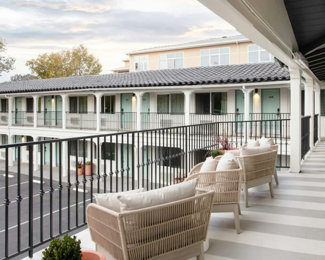 Modern motel balcony seating area with cozy wicker chairs and striped flooring.