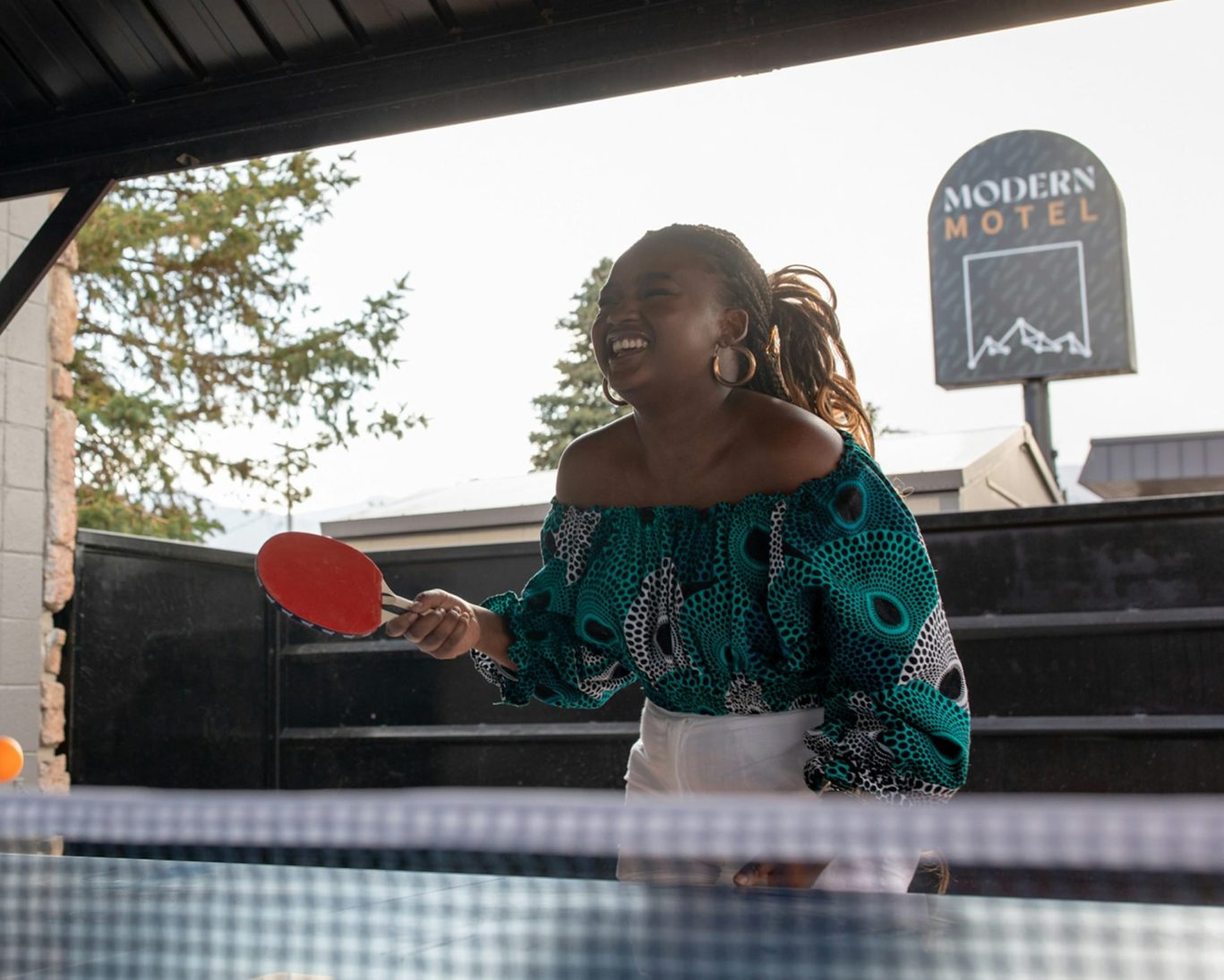 Guest playing table tennis at Modern Motel outdoor recreation area.