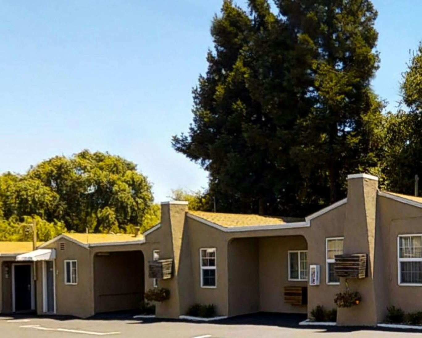 Charming exterior of Discovery Inn guest rooms with private entrances and on-site parking surrounded by trees.