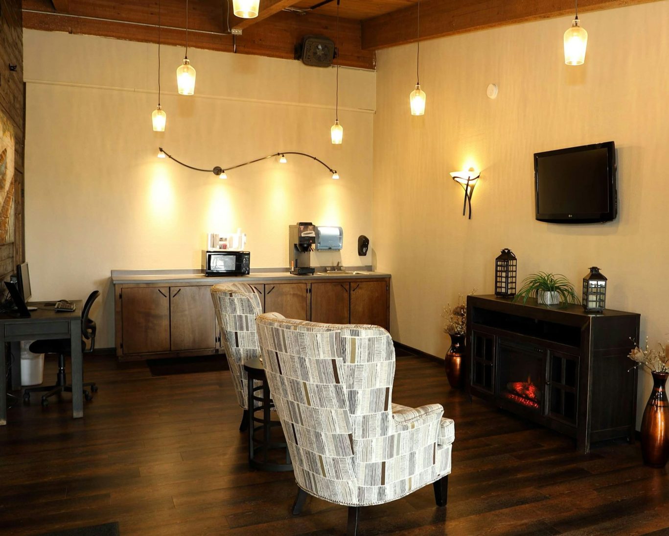 Cozy lobby at Northern Lights Inn featuring lounge seating, flat-screen TV, fireplace, and complimentary beverage station.