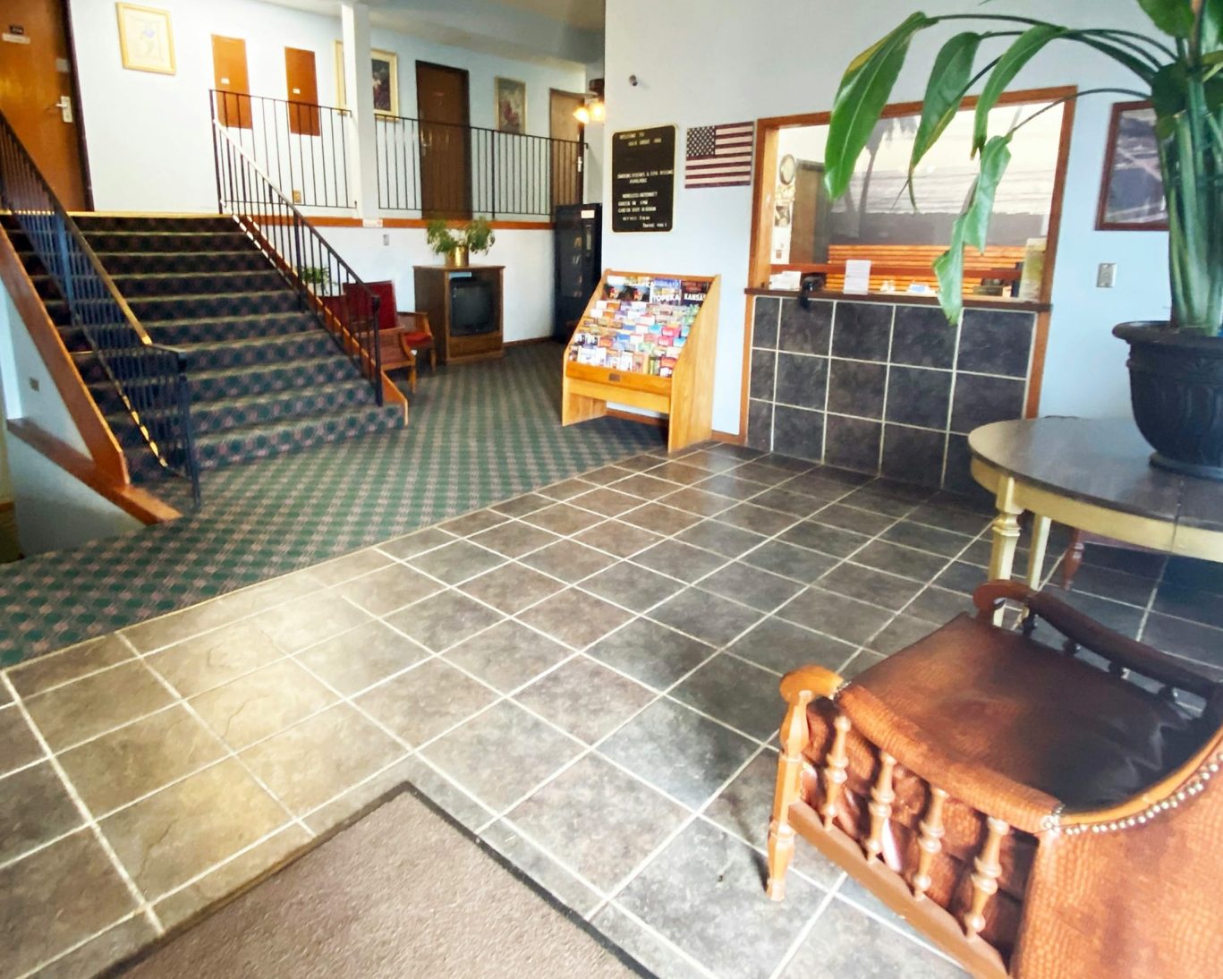 Spacious hotel lobby at Oak Grove Inn featuring tiled floors, front desk, staircase, and guest seating.