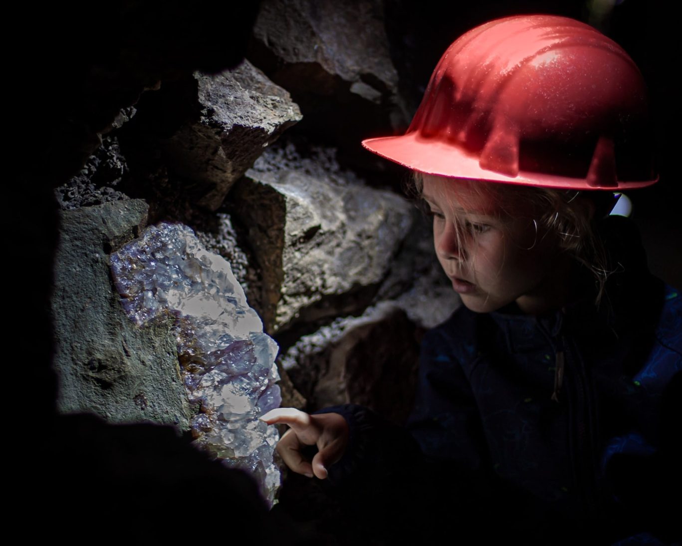 Child exploring crystals inside Edelsteinminen Steinkaulenberg gemstone mine in Idar-Oberstein, Germany.