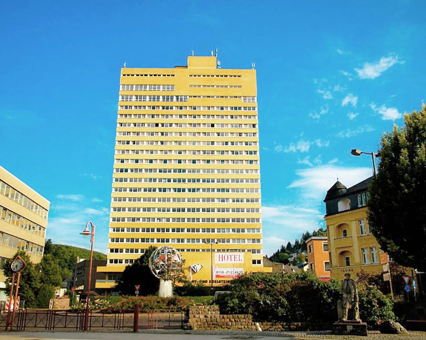 Tall yellow Opal Hotel building in Bad Kreuznach, Germany with clear blue sky.