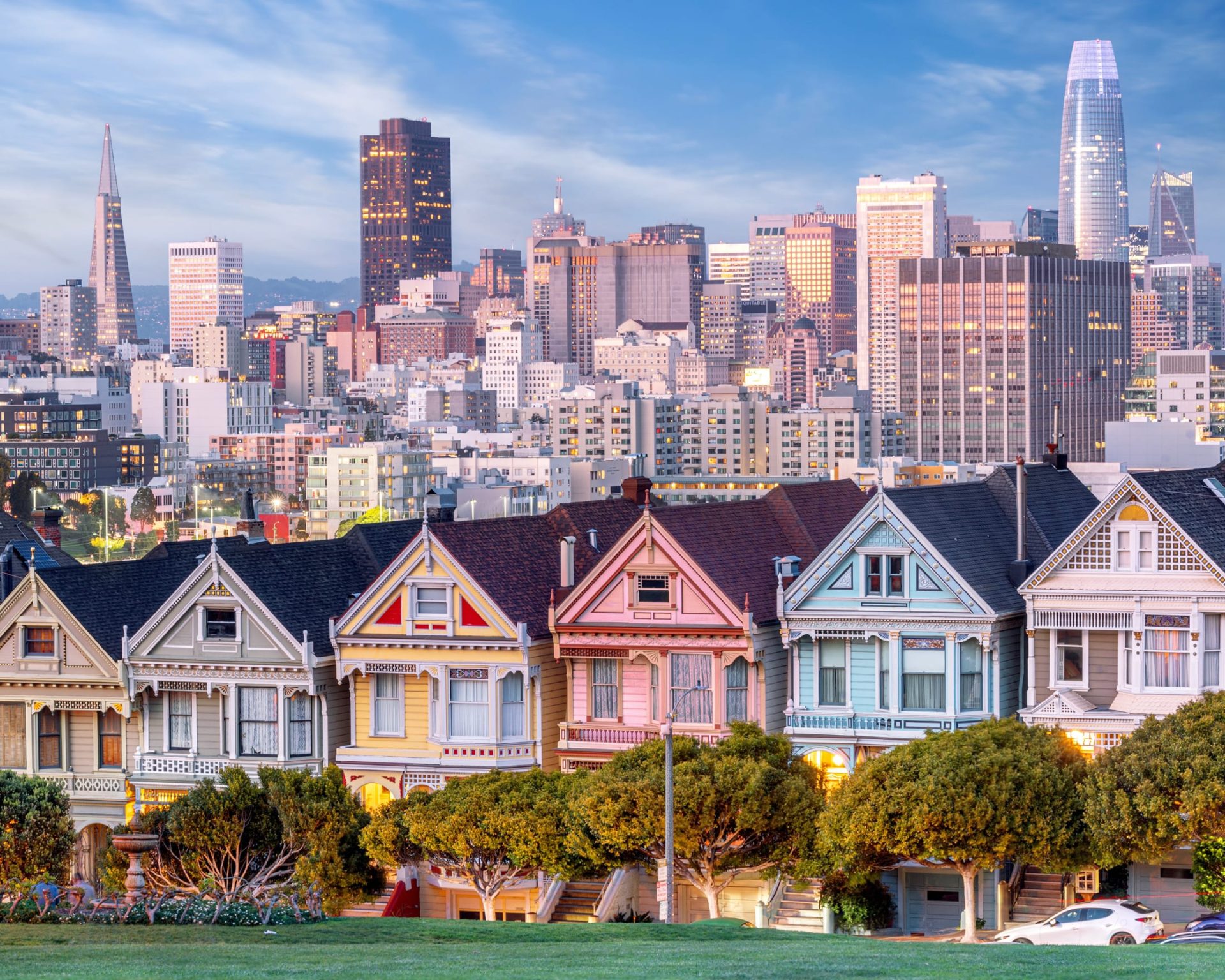 Famous Painted Ladies Victorian houses with the San Francisco skyline in the background at sunset.