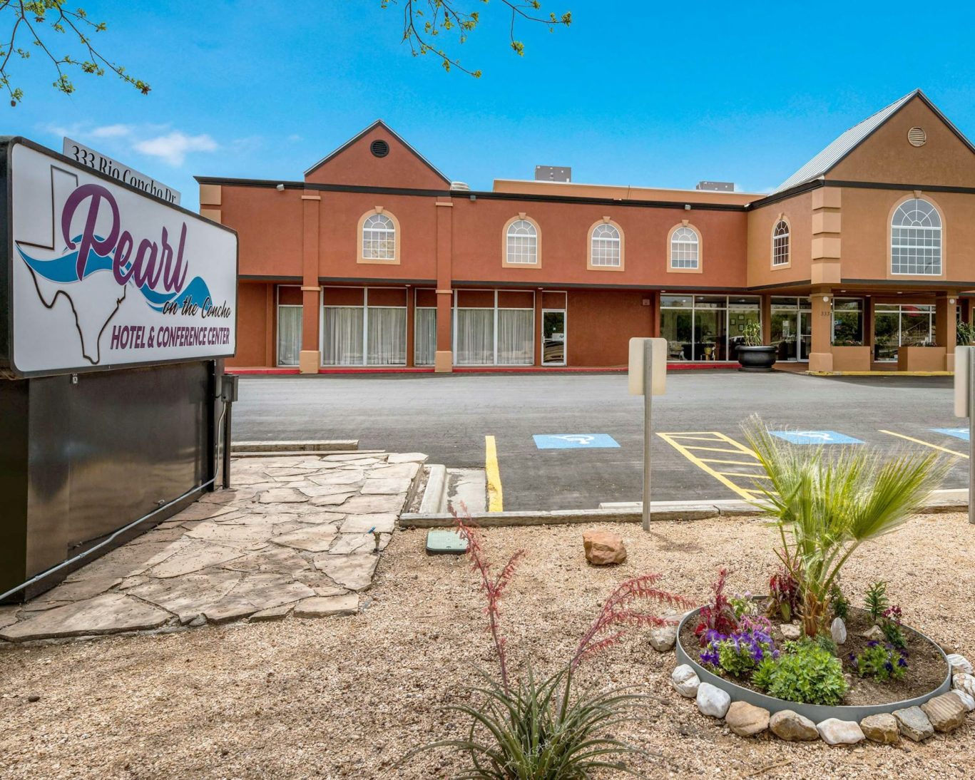 Front exterior of Pearl on the Concho Hotel & Conference Center in San Angelo, Texas, featuring hotel sign and accessible parking.