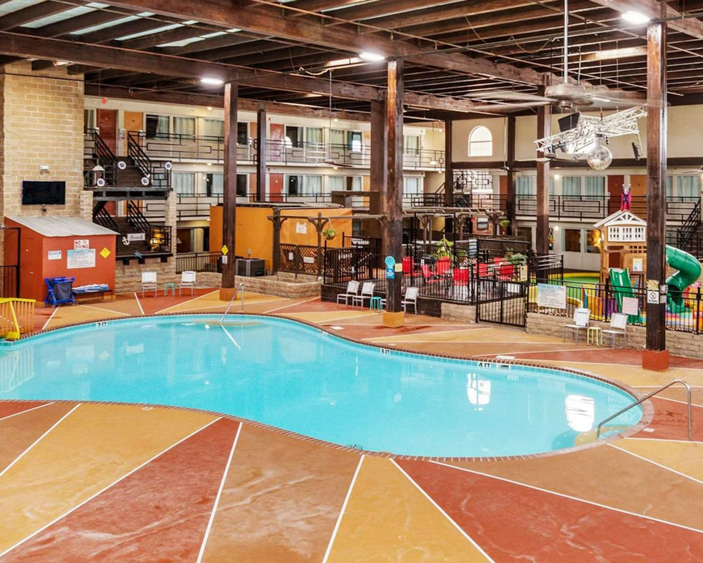 Spacious indoor pool area at Pearl on the Concho Hotel in San Angelo, TX, surrounded by guest rooms and family-friendly play zones.