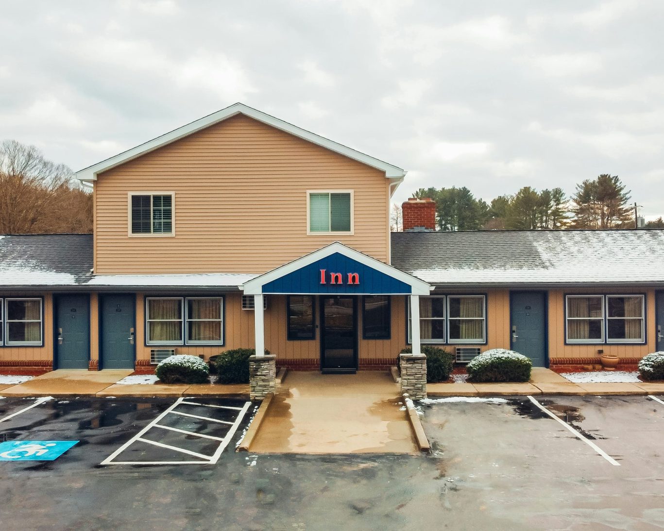 Main entrance and accessible parking at Quiet Corner Inn Brooklyn CT with two-story guest building in winter.