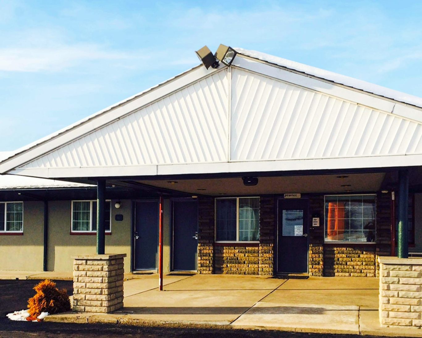 Front entrance and reception area of Relax Inn Bloomsburg under a clear blue sky.