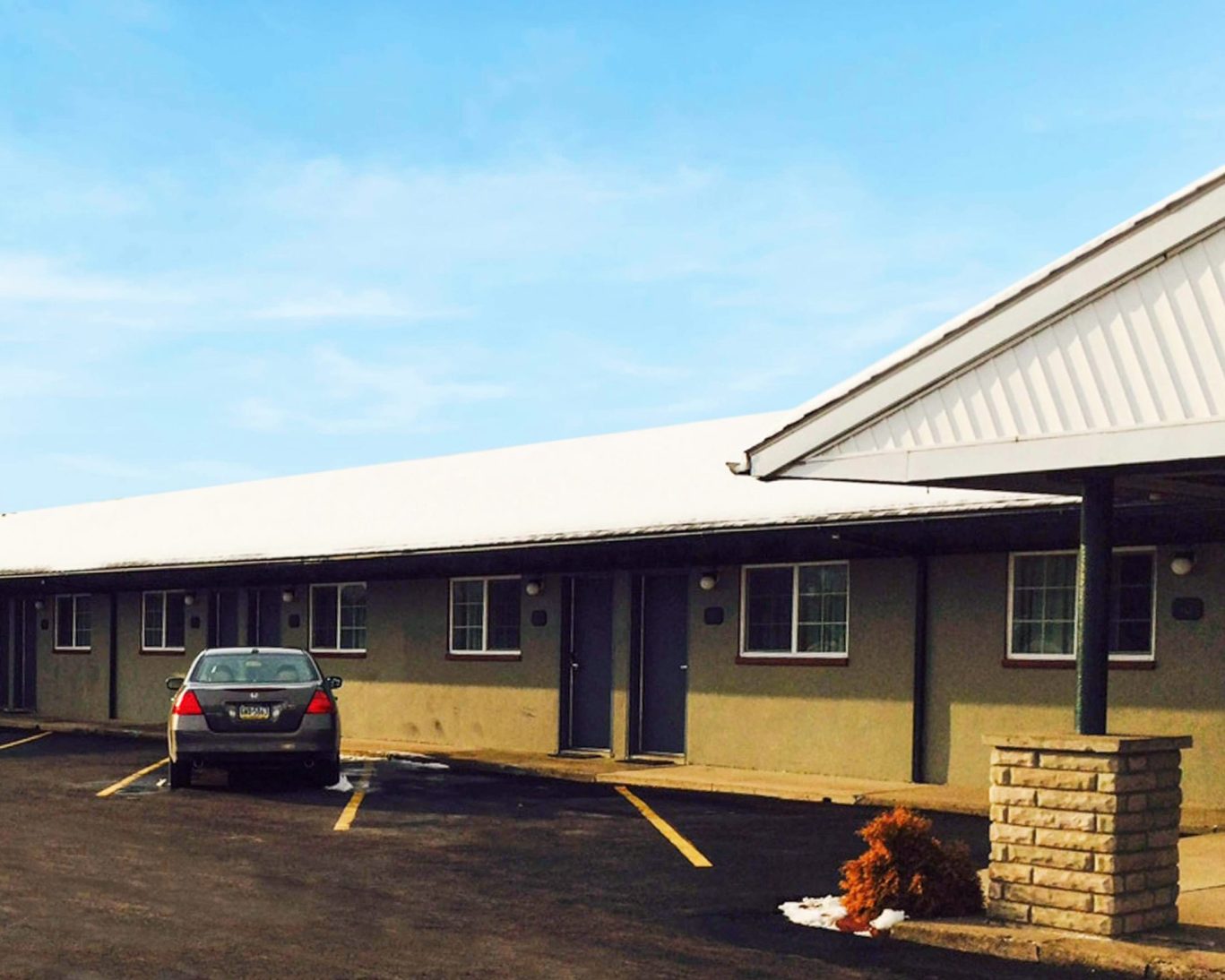 Side view of Relax Inn Bloomsburg with guest parking and snow-dusted rooftop.