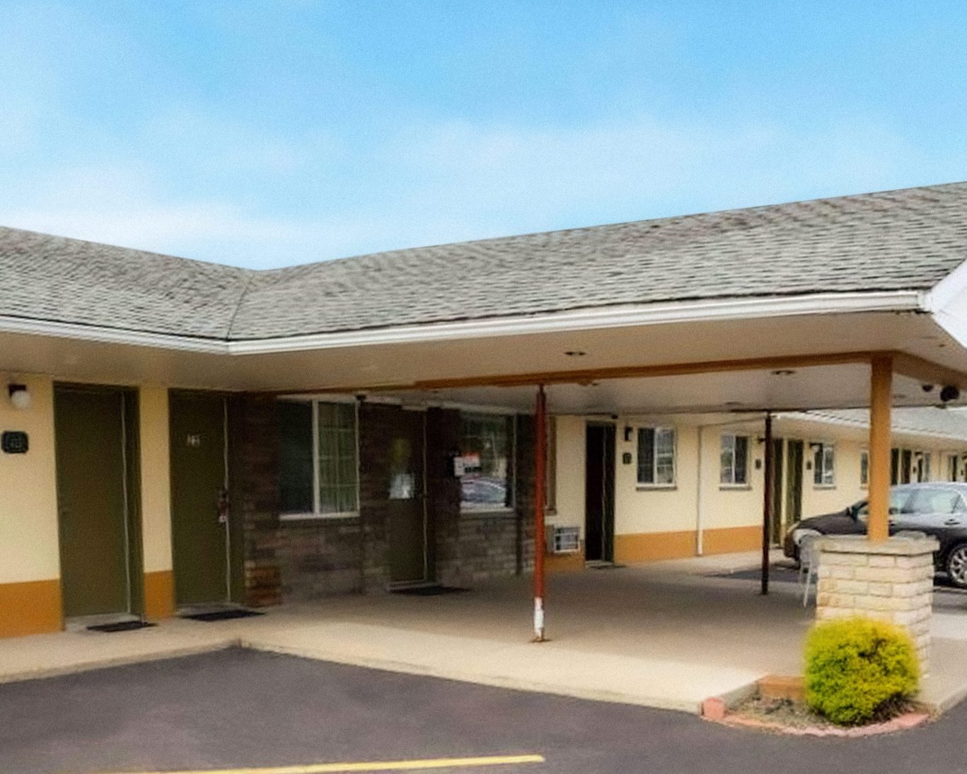 Exterior view of Relax Inn Bloomsburg showing parked vehicles and guest rooms.