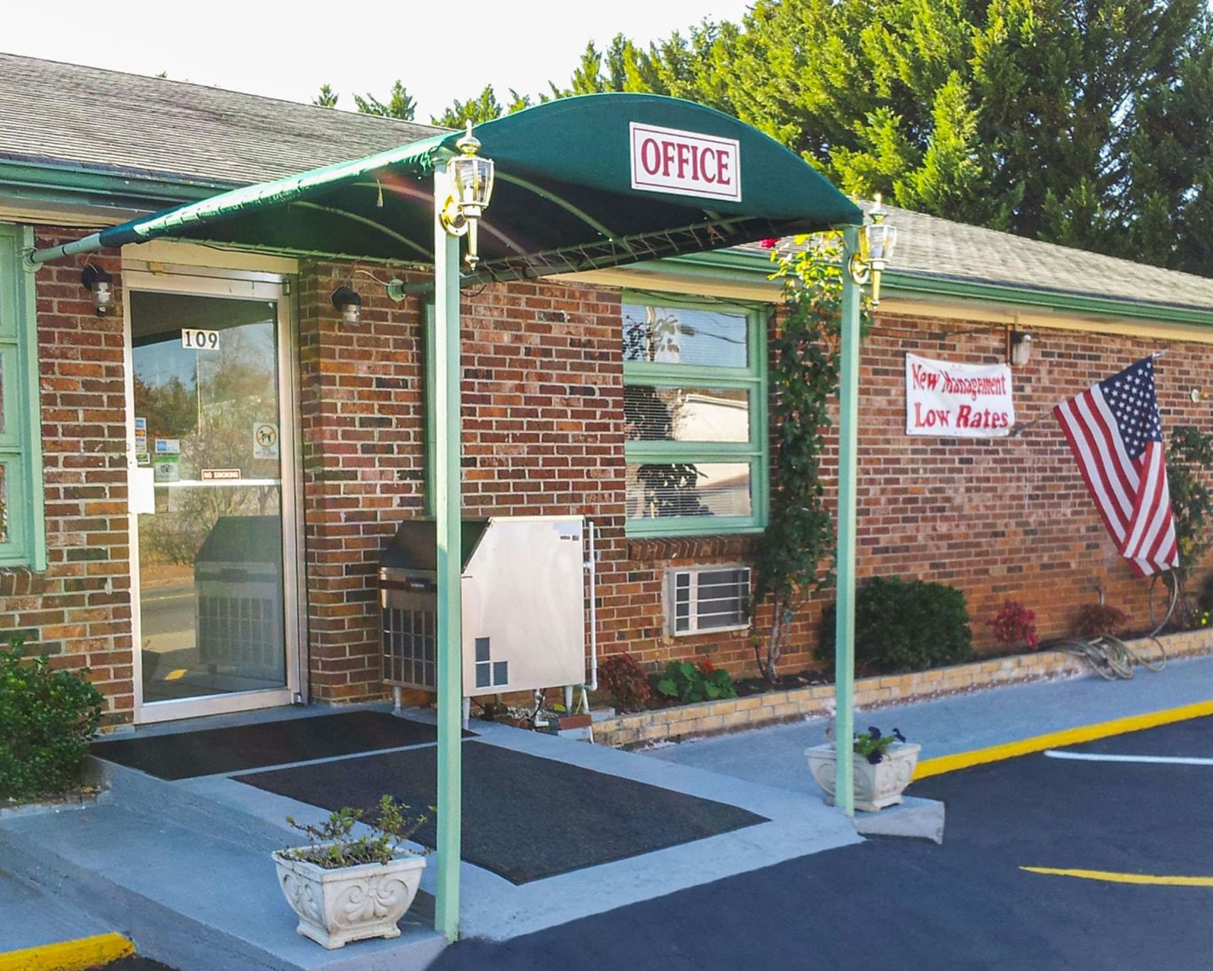 Relax Inn Westminster motel entrance with office sign and American flag display.