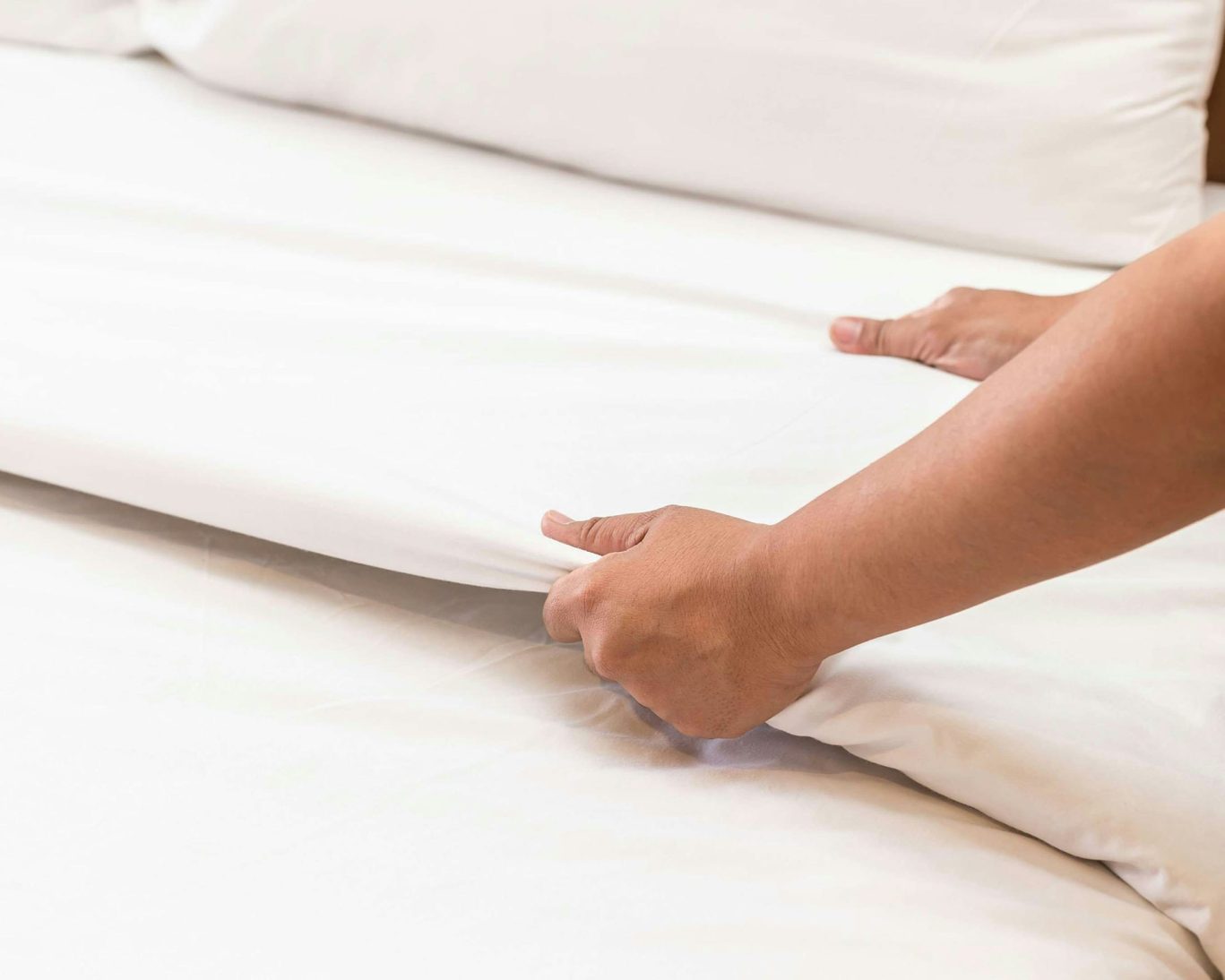Hotel staff making a clean white bed at Relax Inn Westminster.