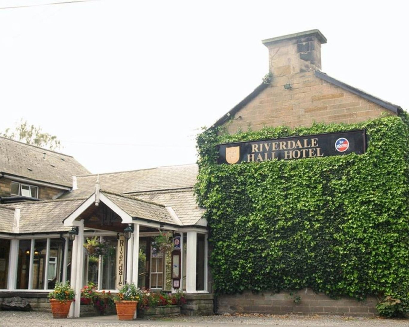 Front entrance of Riverdale Hall Hotel with ivy-covered stone facade and visible hotel signage.