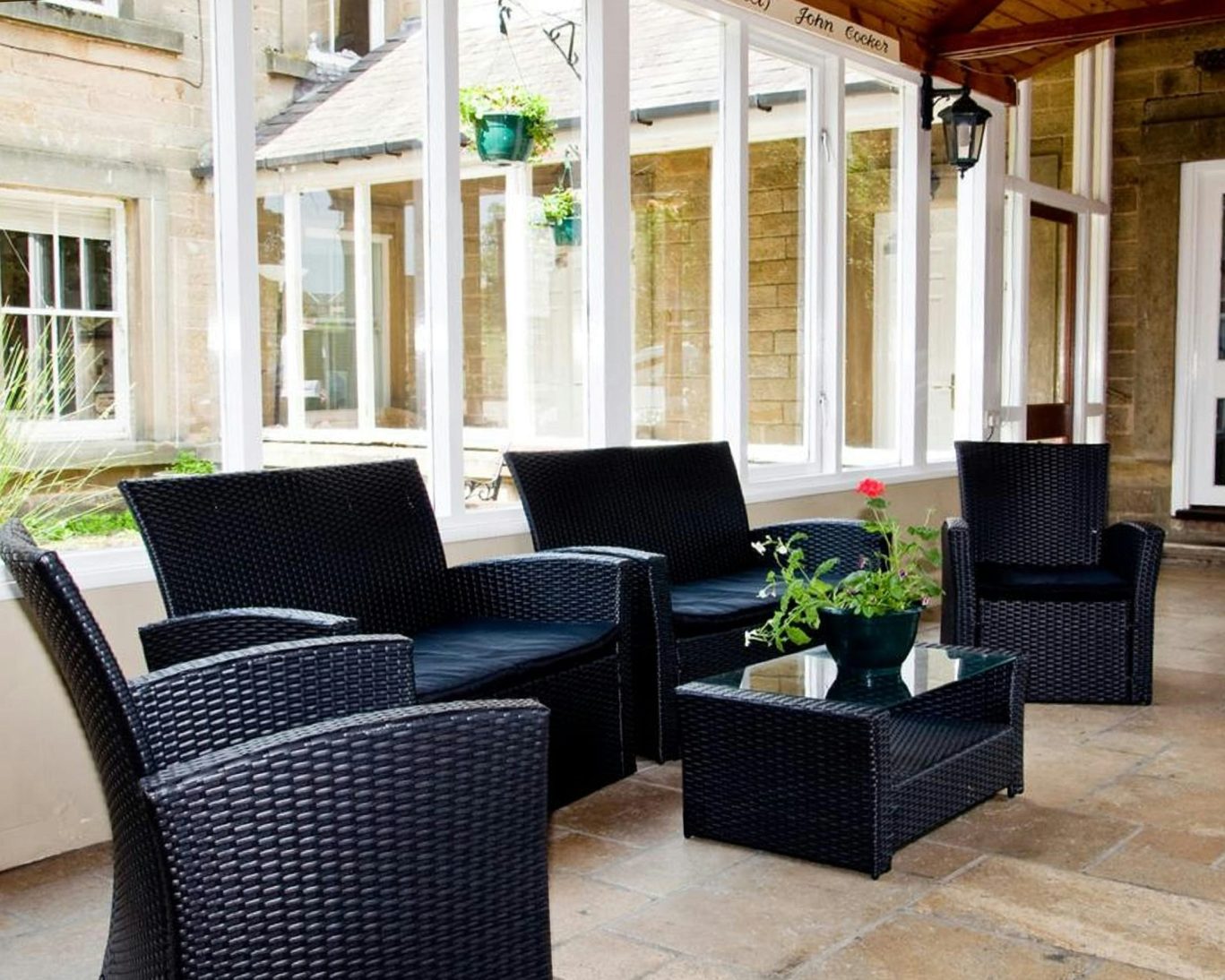 Bright conservatory lounge area at Riverdale Hall Hotel with wicker seating and potted plants.