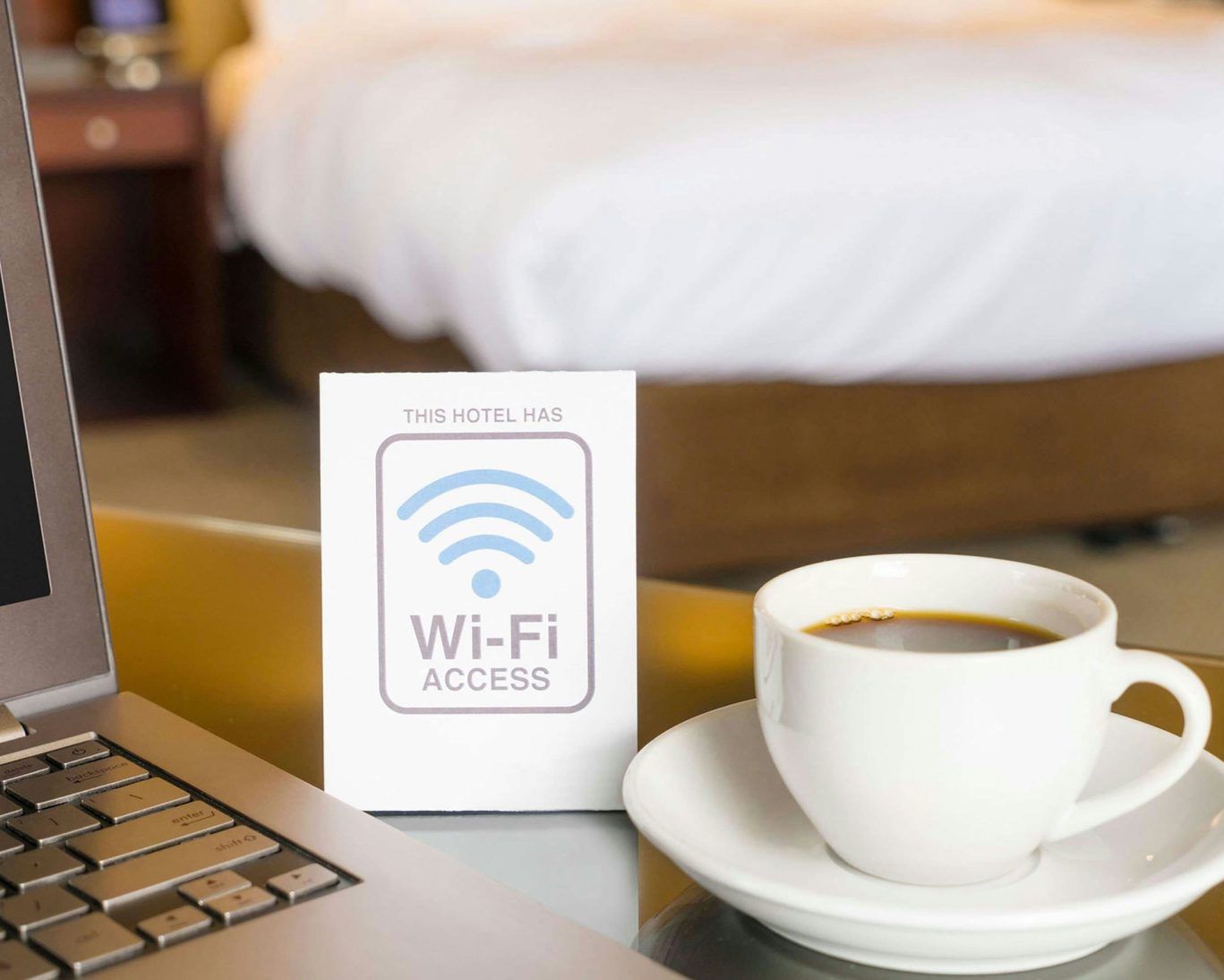 Close-up of Wi-Fi access sign and coffee cup beside laptop in Royal Inn Motel room.